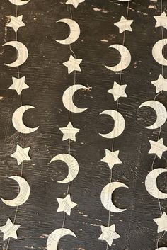 some white stars and crescents hanging from strings on a wooden surface with black background