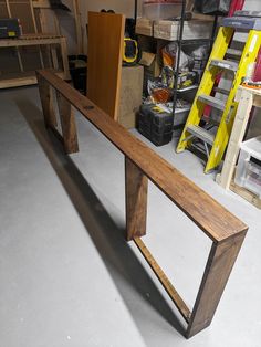 a wooden bench sitting in a garage next to some shelves and tools on the floor