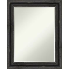 a black framed mirror on a white wall with a wooden frame and metal trim around the edges