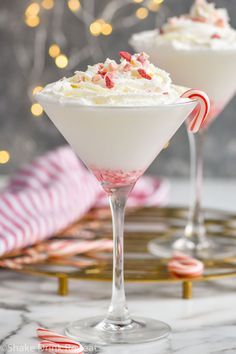 two martini glasses filled with white chocolate and candy canes on a marble table top