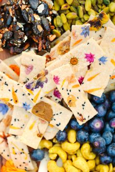 an assortment of fruits and nuts on a plate with crackers in the middle, including blueberries, almonds, pistachios, and more