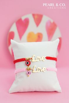 two bracelets with the word love on them are sitting next to a white pillow