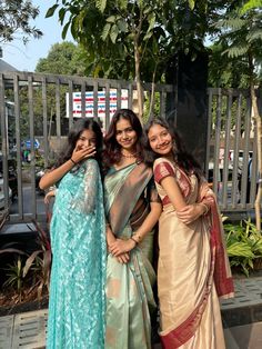 three women standing next to each other in saris and holding their arms around one another