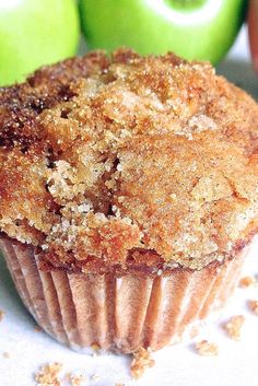 a muffin sitting on top of a white plate next to green apples