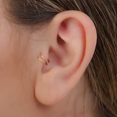 a woman's ear is shown with two small gold rings on the side of her ear