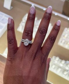 a woman's hand with a diamond ring on top of her finger in front of a keyboard