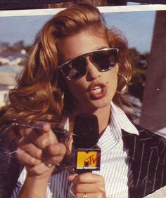 a woman wearing sunglasses and holding a microphone in front of her face with the word m on it