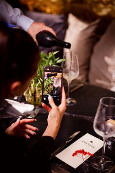 a woman is taking a photo with her cell phone at a table full of wine glasses