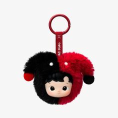 a red and black keychain with a doll in it's head hanging from the front