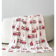 a red and white fire truck blanket sitting on top of a couch next to a pillow