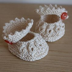 two crocheted baby shoes sitting on top of a wooden table