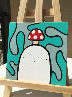 an easel with a painting of a mushroom on it's back and blue background