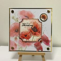 an easel holding a card with red flowers on it