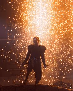 a man standing on top of a rock in front of fireworks