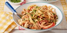 two bowls filled with pasta and vegetables on top of a table next to a yellow towel