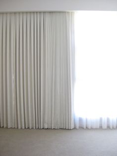 an empty room with white curtains and carpet