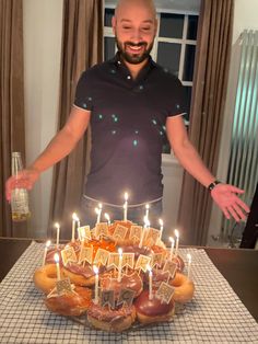 a man standing in front of a cake with candles on it