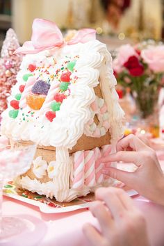 a person decorating a gingerbread house with candy and sprinkles on it