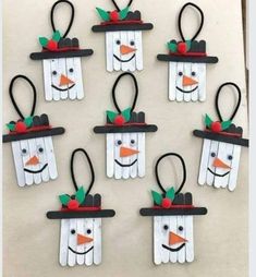 snowmen made out of popsicle sticks are hanging on the wall with hats and bows