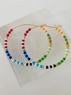 Colorful glass rainbow beads adorn a gold hoop earring. These lightweight earrings are so versatile. Trendy Beaded Earrings, Rainbow Bead Earrings, Seed Bead Hoop Earrings, Hoop Earrings Diy, Gold Hoop Earring, Engagement Mehndi Designs, Earrings Summer, Summer Earrings, Rainbow Beads