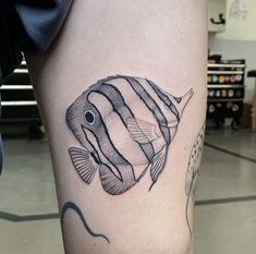 a small fish tattoo on the right thigh, and an image of a fish in black ink