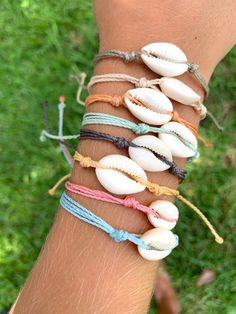 a woman's arm with several seashells on it and string bracelets