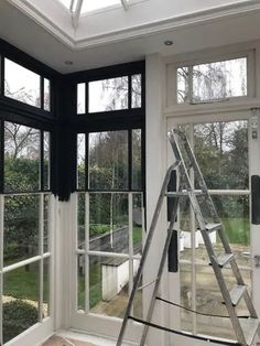 a ladder is in the middle of a room with large windows and an open roof