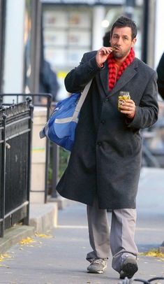 a man walking down the street while talking on his cell phone and holding a drink