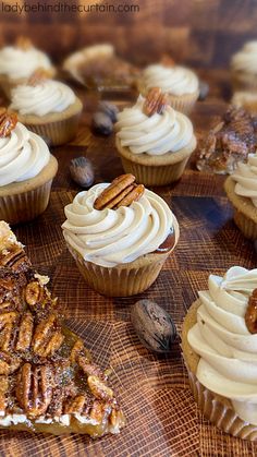 cupcakes with white frosting and pecans are on a wooden table top