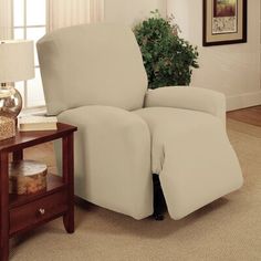 a living room with a white recliner next to a coffee table and potted plant