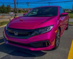 a pink honda civic is parked on the side of the road in a parking lot