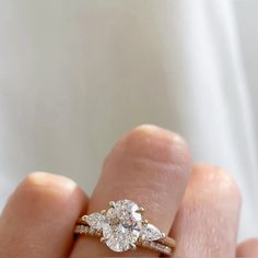 a close up of a person's hand holding a ring with three diamonds on it