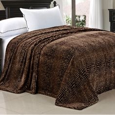 a bed covered in a brown blanket next to a night stand with two nightstands