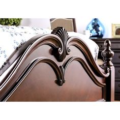 a close up of a bed with wooden headboard and foot board