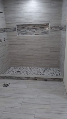 a white tiled bathroom with wood flooring and tile on the shower wall, along with a toilet