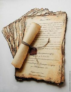 an old scroll and some paper on top of each other with a small piece of string attached to it