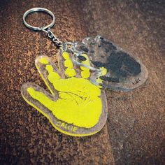 a yellow handprint on a clear plastic keychain with a black rubber backing