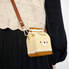 a woman is holding a small purse with a bear face on the front and side