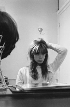 a black and white photo of a woman looking in the mirror