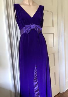 Step back into the 1970s with this lovely deep purple velvet dress, featuring exquisite satin accents and a dramatic floor-length design. Perfect for formal occasions, vintage events, or making a bold fashion statement. Complete the look with elegant heels and statement jewelry -a-line, floor-length column skirt creates an elongating effect -fitted empire waist, accentuated with a satin sash and bow detail at the front -satin ruffle trim at the waist, extending down the front of the skirt and wr Velvet Holiday Dress, Purple Velvet Dress, Purple Gowns, Column Skirt, Elegant Heels, Velvet Gown, Full Length Gowns, High Waist Dress, Empire Waist Dress