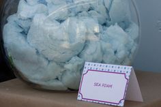 a jar filled with blue sea foam next to a sign that says sea foam on it