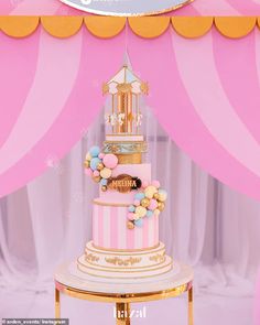 a pink and gold wedding cake with birdcage on top is surrounded by balloons