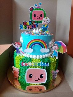 a birthday cake in the shape of a house with cartoon characters on it and rainbow decorations