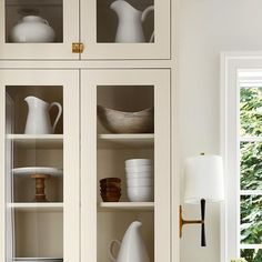 a white china cabinet filled with dishes and cups