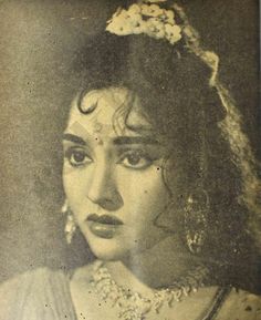 an old black and white photo of a woman with long hair wearing a headdress