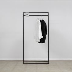 an iron clothes rack with two shirts hanging on it