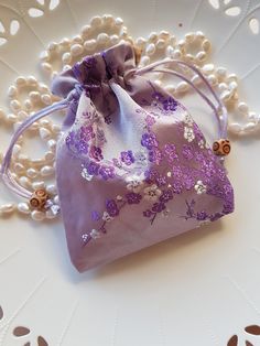 These are Gorgeous Lux silk bags in a beautiful shade of Soft Mauve, they feature a Lovely Cherry Blossom design stitched in beautiful Purples and White tones, truly elegant. The silk bags are lined inside and have a Satin draw string which makes them easy to use, and they have two nice wooden beads as a feature. The bags are approximately 11.5cm Wide and 14.5cm in length. There maybe slight variation in size of the bag and placement of the beautiful print as these were handmade. The Silk fabric is Beautiful and Lush and are perfect to elevate your Gift giving. Elegant Purple Bag Gift, Purple Embroidered Bag For Gift, Elegant Pouch-shaped Potli Bag As Gift, Elegant Potli Pouch Bag As Gift, Elegant Potli Bag For Gifts, Cherry Blossom Design, Pouch Bags, Silk Bag, Blossom Design