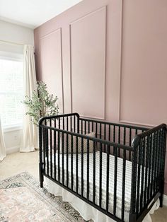 a baby crib in front of a pink wall