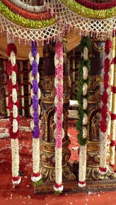 an elaborately decorated shrine with flowers on the floor and pillars in front of it