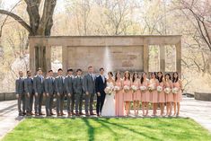 a group of people standing next to each other in front of a building and trees